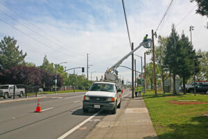 Utility workers move lines to new poles